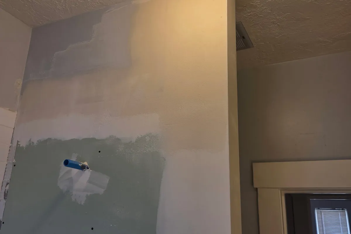 Drywall wall with skim-coat repair patches feathered and blended into the surrounding finish